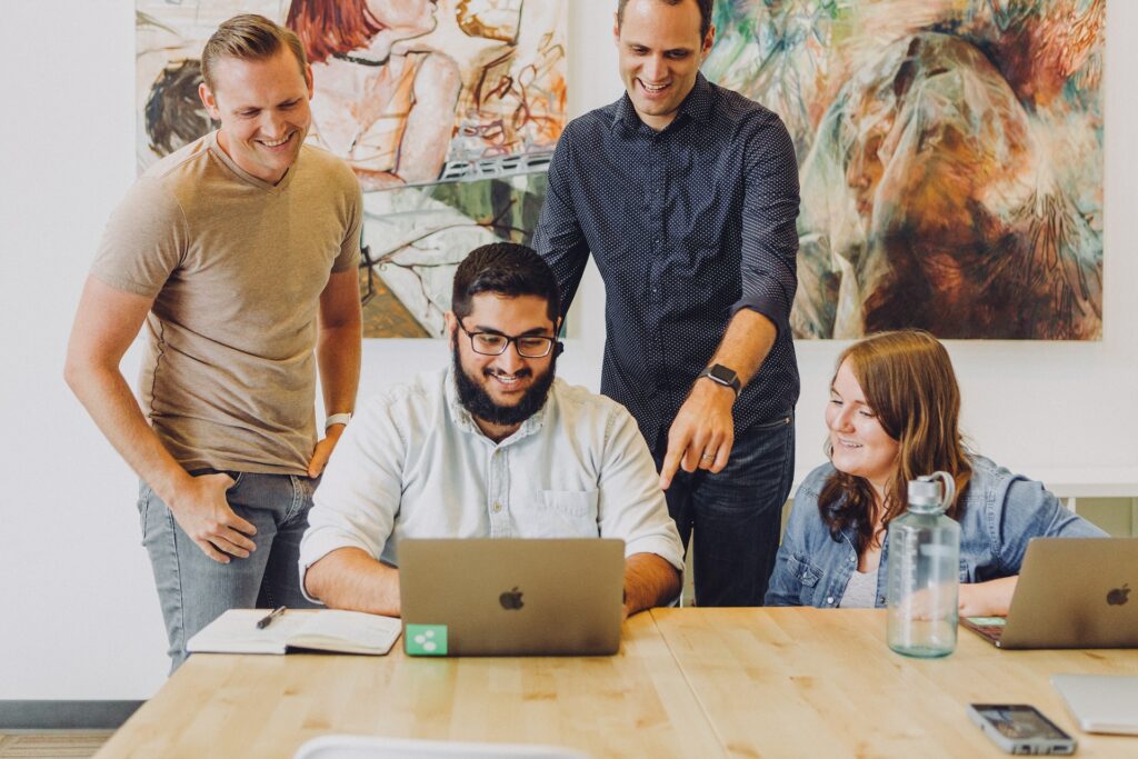 a man at a computer and a group of people nearby